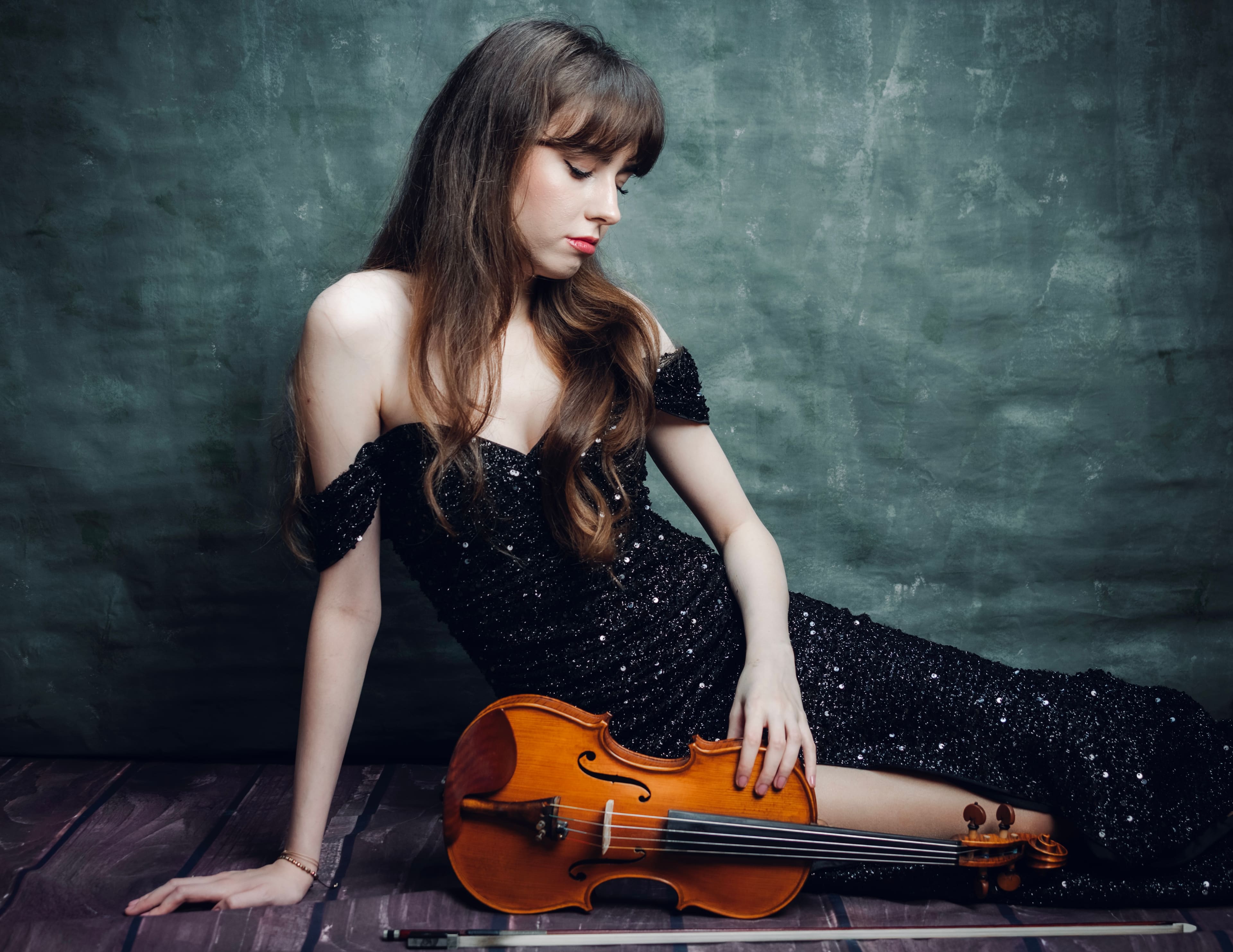 One of the sisters seated on the floor with her instrument